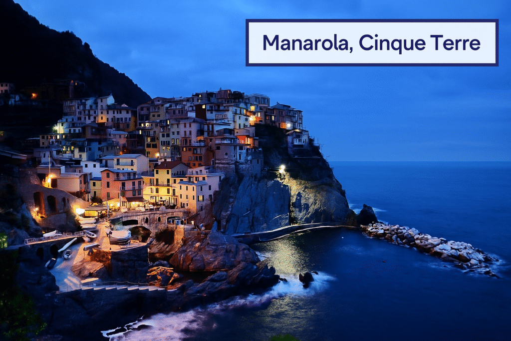 Colorful cliffside houses of Manarola, Cinque Terre, illuminated at twilight above the blue Ligurian Sea.