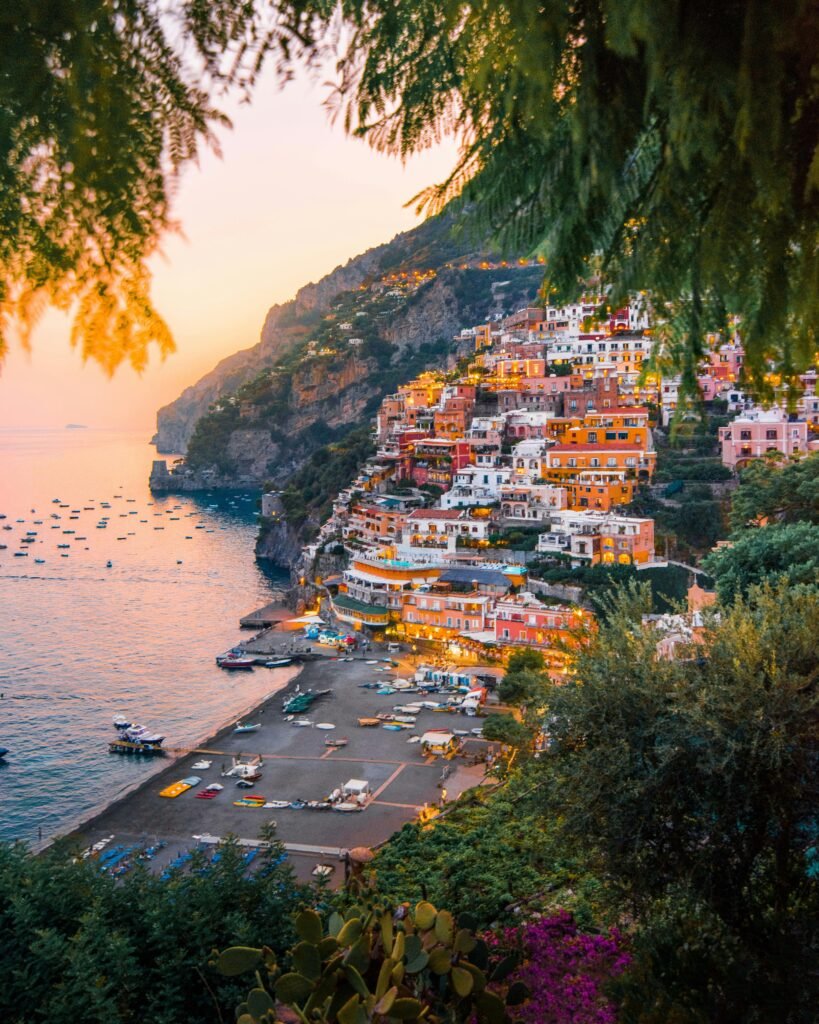 Colorful cliffside houses in Manarola, one of the most beautiful small towns to visit in Italy, overlooking the turquoise Ligurian Sea at sunset.